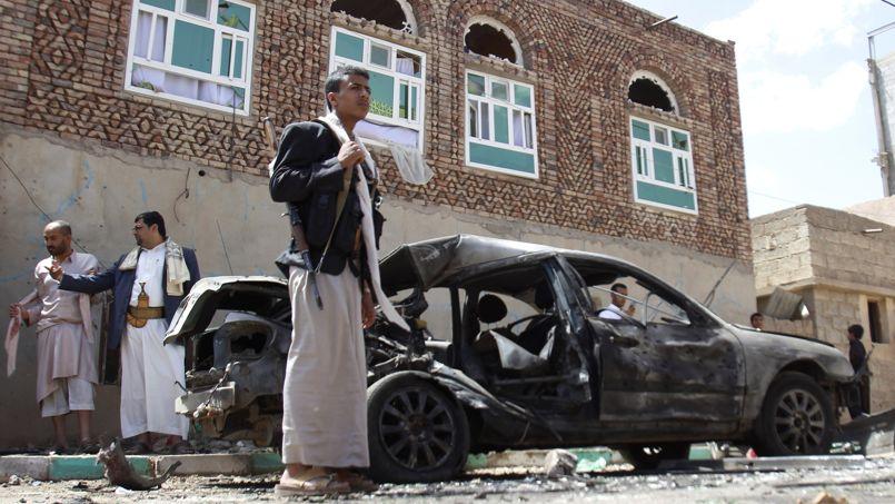 Un milicien Houthi devant une voiture endommagée par l'attaque suicide, le 20 mars 2015 à Sanaa, capitale du Yémen.
