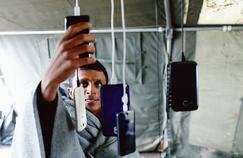 A migrant checks the battery from the smartphone before to cross the border between Serbia and Croatia, October 18, near the village of Berkasovo, Serbia.