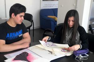 Nadeen expose ses dessins à Khaldoun, un bénéficiaire du réseau Nawaya.