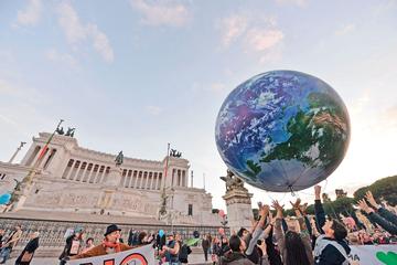Des Italiens jouent avec un immense ballon représentant la Terre, lors d'un rassemblement pour le climat, dimanche, sur la Piazza Venezia, à Rome.