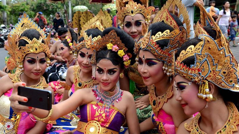 Indonésie. A Denpasar sur l'île de Bali, des jeunes filles prennent un selfie au cours de la célébration du Nouvel An. Les danses et la musique diversifiées et nombreuses de l'île touristique font sa célébrité.