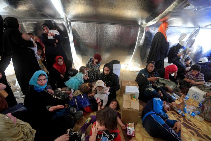 Des familles fuyant l'Etat islamique attendent d'être fouillées à un check point de Mossoul. L'armée irakienne craint la présence de kamikazes parmi eux