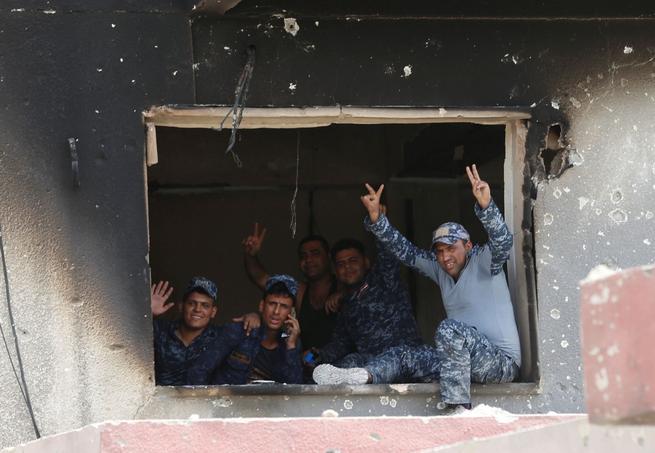 Des policiers irakiens font le V de la victoire durant les combats dans la vieille ville, qu'ils espèrent reprendre à l'Etat islamique d'ici la fin de la semaine.