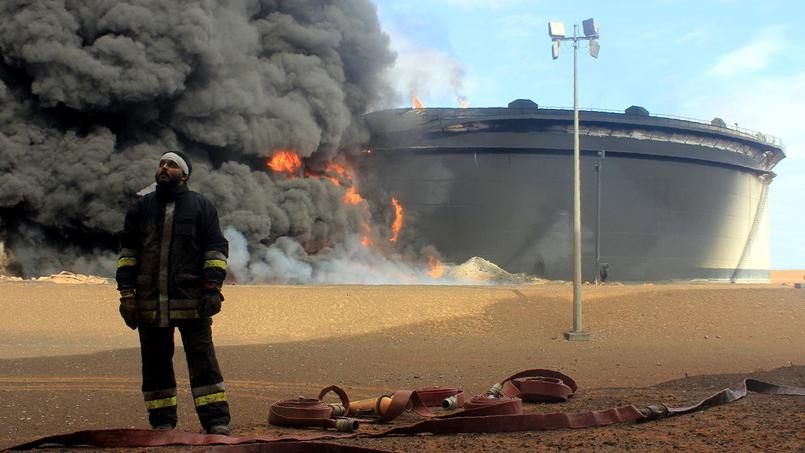 Un pompier libyen devant un réservoir en feu sur le centre de raffinage de Ras Lanouf après une offensive menée, la semaine dernière, par les militants de Daech en vue de s'emparer des installations portuaires et pétrolières.