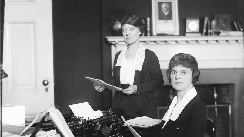 Des femmes travaillant dans un bureau où est affiché un portrait du président Warren Harding. La Journée internationale des droits des femmes est née au début du XXe siècle avec la mobilisation de femmes ouvrières.