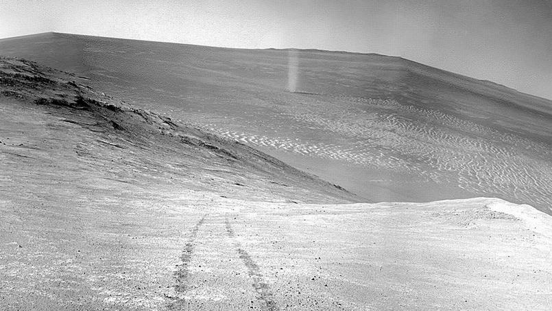 Le tourbillon de poussière est visible au fond du cratère, en contrebas des traces de roues laissées par le rover Opportunity.