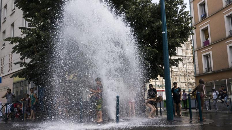 Des enfants sous le geyser provoqué par l'ouverture d'une bouche d'incendie