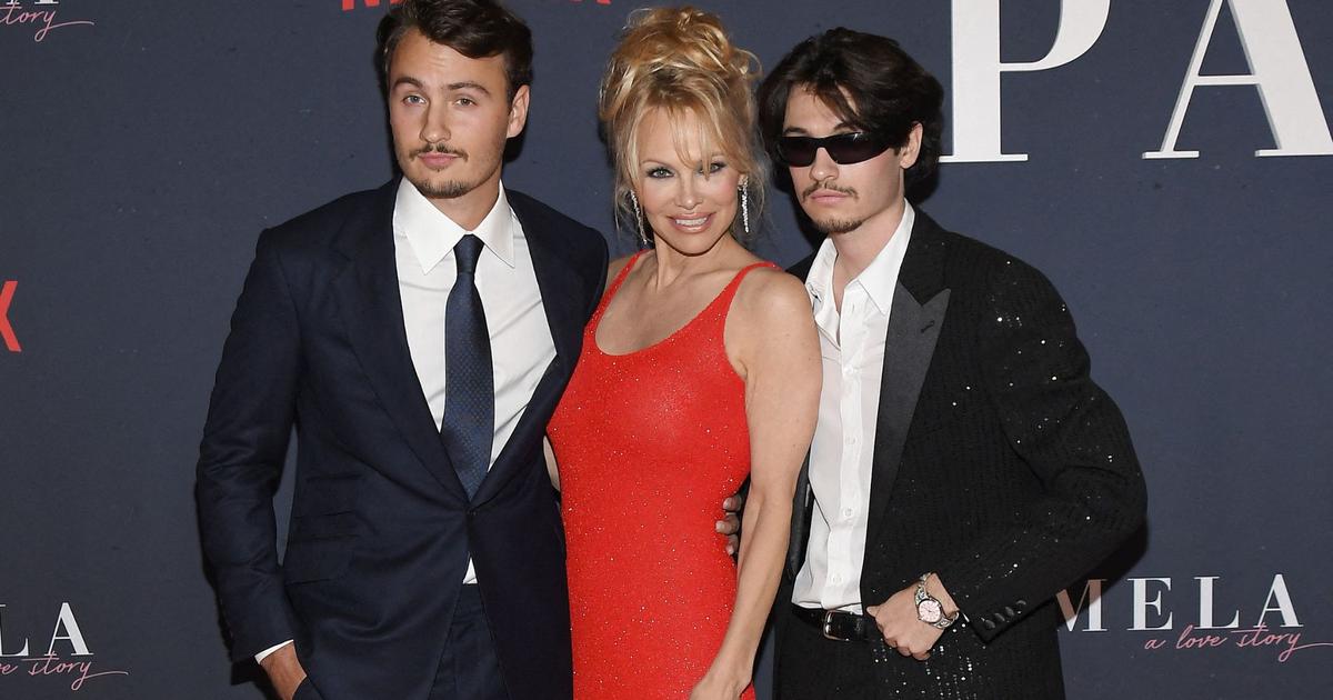 in a tight red dress, Pamela Anderson poses with her two sons, Brandon and Dylan