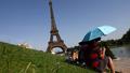 Les touristes aux abords de la tour Eiffel tentent de supporter la chaleur écrasante.