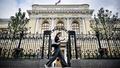 Portable à la main, une jeune femme marche devant la Banque centrale de Russie, à Moscou, en septembre 2023.