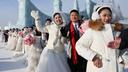 Des couples attendent le début de la cérémonie de mariage de groupe lors du festival de sculptures sur glace de Harbin, en Chine.