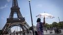 Un touriste se protège du soleil sous un parasol lors d’une vague de chaleur à Paris.