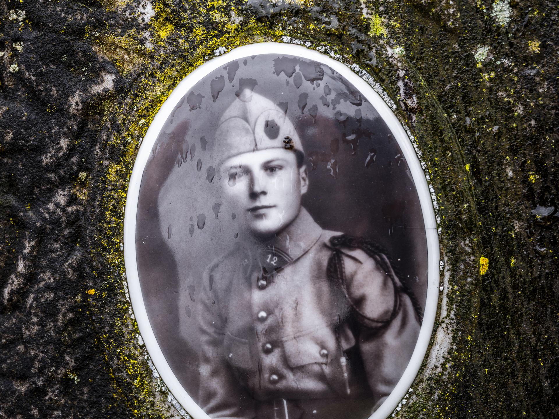 Sur cette sépulture à l’abandon, le visage d’un jeune soldat tué sous la mitraillette.