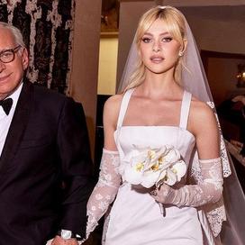 Aux bras de son père, Nicola Peltz Beckham se dirige vers le lieu de cérémonie. (Palm Beach, le 9 avril 2022.)