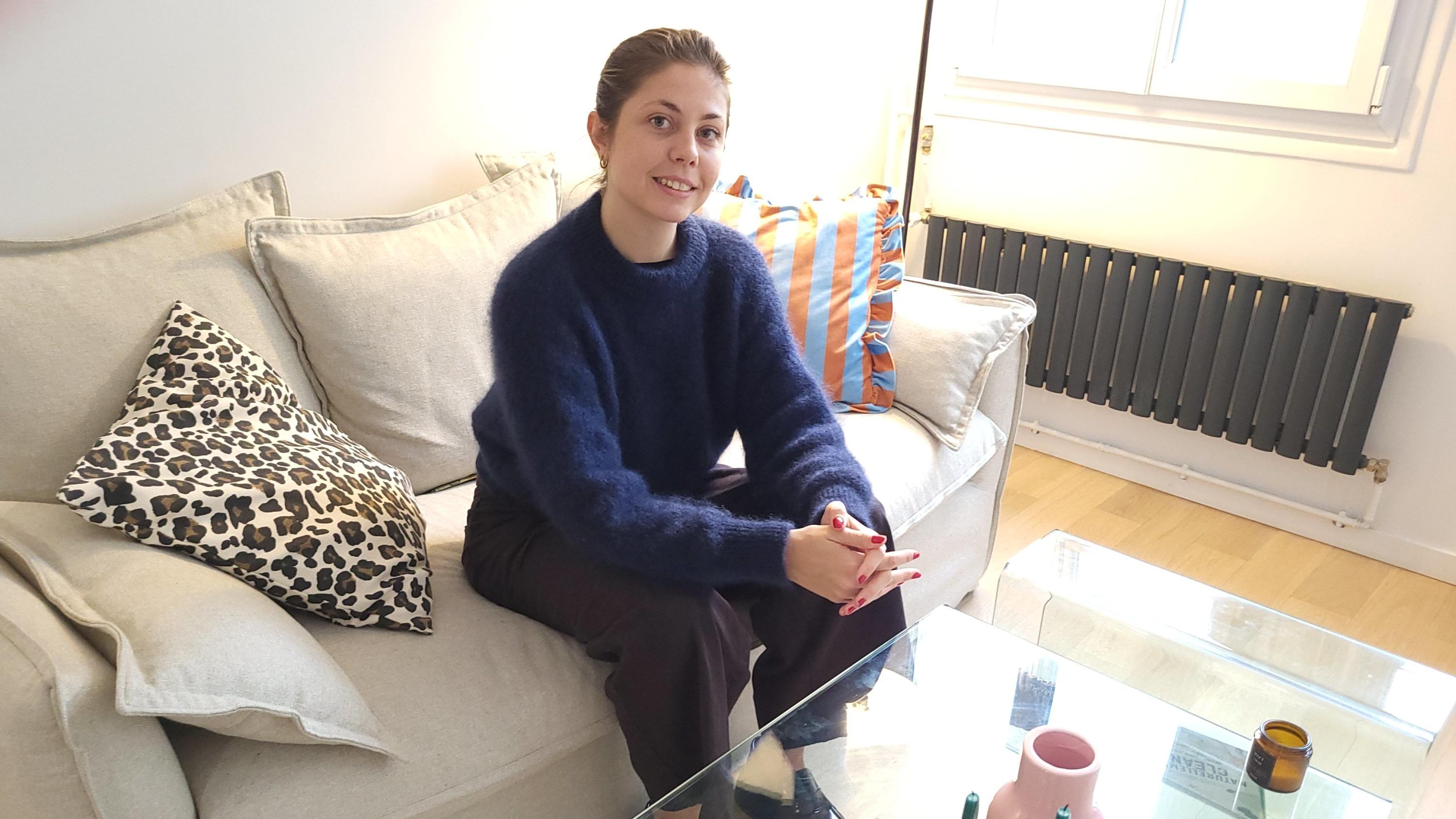 Margot Le Bourge, 26 ans, assise sur le canapé loué à Airnest et qui équipe son 2-pièces du 8e arrondissement de Paris.