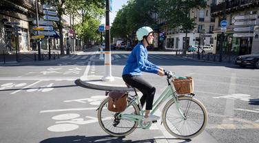 Une femme se rend au travail à vélo, à Paris.