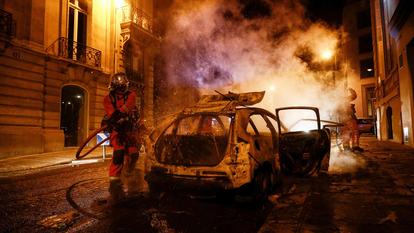 Les pompiers interviennent pour éteindre une voiture en feu, près des Champs-Élysées, dimanche soir.