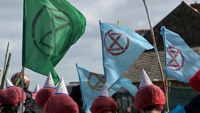 Des militants d’Extinction Rebellion brandissent des drapeaux devant la raffinerie TotalEnergies à Donges, le 23 mars 2024.