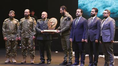 Le président syrien Ahmed al-Sharaa tient un trophée en l’honneur du ministre de la Défense Murhaf Abu Qasra, à l’occasion du premier anniversaire de la chute de Bachar al-Assad, à Damas, en Syrie, le 8 décembre 2025.