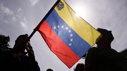 Une personne brandit un drapeau vénézuélien alors que les partisans du gouvernement se rassemblent après que le président américain Trump a déclaré avoir capturé son président Maduro, à Caracas, le 3 janvier 2026.