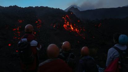 Les visiteurs observent un flux de lave actif après la tombée de la nuit sur les pentes du mont Etna, le 3 janvier 2026