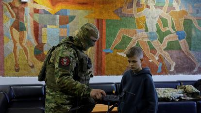 Un membre des forces armées russes montre un drone à un garçon à Donetsk, une ville d’Ukraine contrôlée par la Russie, le 22 février 2026.