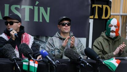 Mo Chara, entouré des autres musiciens de Kneecap, à une conférence de presse à Belfast, le 11 mars 2026. Les poursuites pour « infraction terroriste » le visant ont été abandonnées.