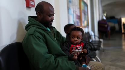 Othman Yahyeh Dawood, 41 ans, avec son fils Mohammed, 10 mois, de Sennar, au Soudan, assis alors que des réfugiés et des travailleurs migrants déplacés s’abritent dans l’église Saint-Joseph.