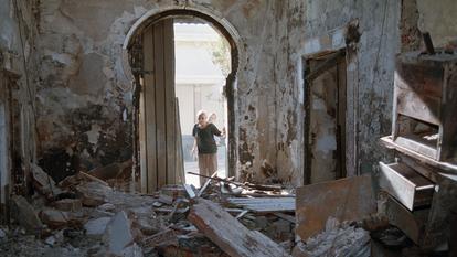 Le romancier reconstitue avec la précision de l’historien le processus à l’œuvre après la révolte de 1988 (ici, deux habitants d’Alger observent les ruines d’un bâtiment incendié par des guérilleros fondamentalistes islamistes, en 1994).