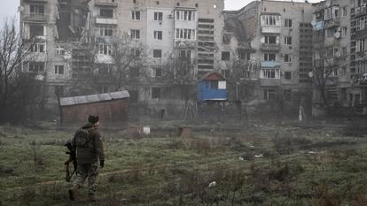 Un membre des forces ukrainiennes marche près de bâtiments résidentiels endommagés par des frappes militaires russes, au milieu de l’attaque de la Russie contre l’Ukraine, dans la ville frontalière d’Orikhiv dans la région de Zaporizhzhia, Ukraine, le 26 mars 2026.