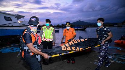 Des membres de l’Agence nationale de recherche et de sauvetage (BASARNAS) transportent un corps retrouvé dans un sac mortuaire lors de l’opération de recherche des réfugiés rohingyas portés disparus.