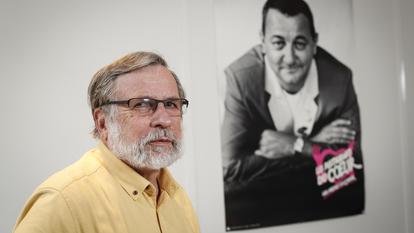 Portrait de Patrice Blanc, président des Restos du Coeur, posant près d’une photo de Coluche, le fondateur de l’organisation.