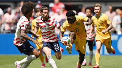 L’Australien Nestory Irankunda en action avec les Américains Joe Scally et Chris Richards lors du match États-Unis/Australie à la Coupe du monde de football.
