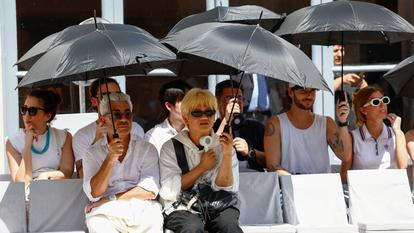 Le public se protège de la chaleur lors d’un défilé de mode à Milan, le 22 juin.