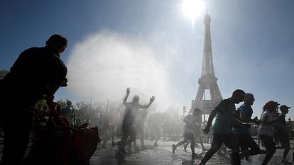 Des coureurs se rafraîchissent sous un jet d’eau devant la Tour Eiffel lors du Marathon de Paris, le 9 avril 2017.