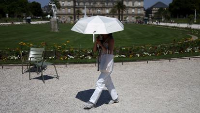 Une personne se réfugie sous un parapluie dans le Jardin du Luxembourg, à Paris, le 27 juin 2026.