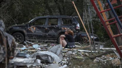Une femme regarde un bâtiment résidentiel endommagé alors qu’elle est assise sur des débris, après des frappes de missiles et de drones russes pendant la nuit à Kiev, en Ukraine, le 2 juillet 2026.