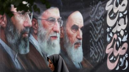 Une femme passe devant une affiche avec les images du regretté leader iranien Ayatollah Ruhollah Khomeini, du regretté leader suprême iranien Ayatollah Ali Khamenei, et du leader suprême iranien, Mojtaba Khamenei, dans une rue de Téhéran le 2 juillet 2026.