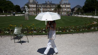 Une femme se réfugie sous un parapluie dans le Jardin du Luxembourg pendant la canicule à Paris, le 27 juin 2026.