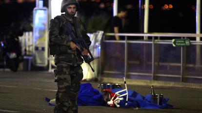 Un soldat se tient près d’un corps recouvert d’un drap bleu sur la Promenade des Anglais, à Nice (Côte d’Azur), le 15 juillet 2016, après l’attentat.