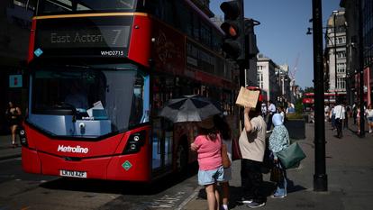 Des passants utilisent des parapluies et des sacs de courses pour se protéger du soleil en attendant de traverser Oxford Street, à Londres, le 23 juin 2026.