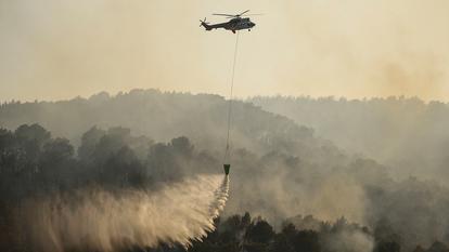 Un hélicoptère de lutte contre les incendies déverse de l’eau sur une zone touchée par un incendie de forêt près de Cotignac, le 23 juillet 2026.