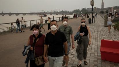Des habitants portant des masques, dimanche, dans le centre de Bordeaux envahi par les fumées des feux de forêt.