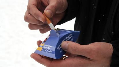 Un homme éteint son mégot de cigarette.