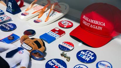 Badges, goodies et casquette Maga dans les vitrines de l’exposition consacrée à la démocratie au musée national de l’Histoire américaine.