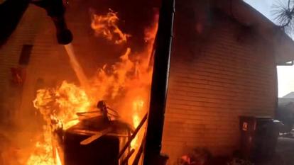 Un pompier s’efforce d’éteindre un incendie dans une maison alors qu’un feu de forêt fait rage dans le comté de Spokane, dans l’État de Washington, aux États-Unis, le 1er août 2026.