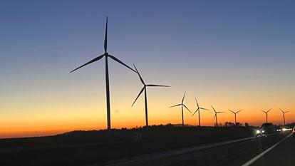 Des éoliennes le long d'une autoroute.