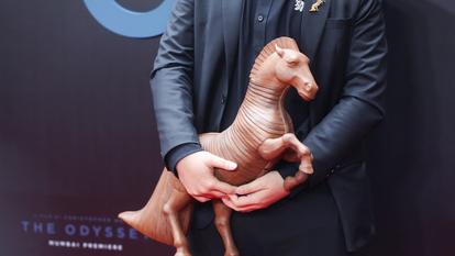 Un influenceur tient une réplique du cheval de Troie, sur le tapis rouge, lors de la première à Mumbai de The Odyssey, en Inde, le 11 juillet 2026.