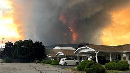 La fumée s’élève de l’incendie de la Bald Range au-dessus d’une rue résidentielle à Summerland, en Colombie-Britannique, Canada, le 7 août 2026.