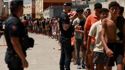 Des migrants font la queue pour recevoir des denrées alimentaires à Ceuta.